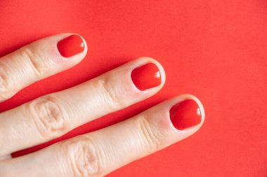 Kırmızı manikürlü kadın elleri izole edilmiş arka planda.