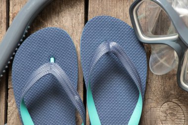 Dalış maskesi ve plaj mavisi terlikler ahşap zeminde, deniz tatili