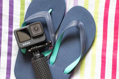 Ukrayna Dnepr 20.04.2021 - GoPro HERO 9 Siyah ve plaj terlikleri, renkli çizgili arka plan, plaj temalı