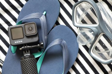 Ukrayna Dnepr 20.04.2021 - GoPro HERO 9 Siyah ve plaj terlikleri çizgili arka planda, tatile hazırlanıyor