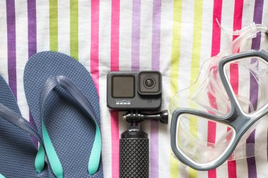 Ukrayna Dnepr 20.04.2021 - GoPro HERO 9 Siyah ve plaj terlikleri çizgili arka planda, tatile hazırlanıyor