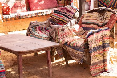 Mısır 'da bir oda çadırında eski renkli halıları olan bir masa ve iki tahta koltuk, Afrika' da bir çadırda eski mobilyalar.