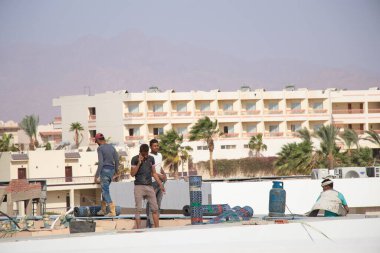 Mısır Sharm El Sheikh 26.04.2021 - inşaat halindeki bir binanın çatısında inşaatçılar, bir otel inşaatı