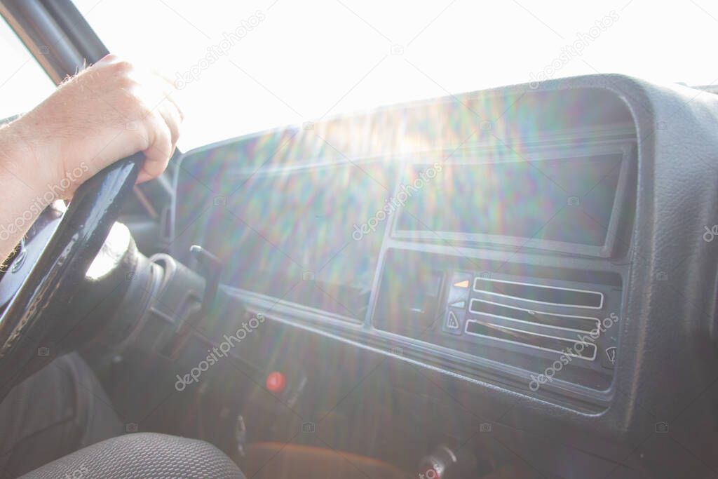 male hands on the steering wheel of an old soviet car on the way in the sun close up