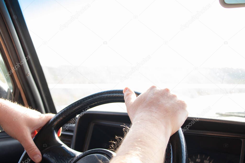 male hands on the steering wheel of an old soviet car on the way in the sun close up