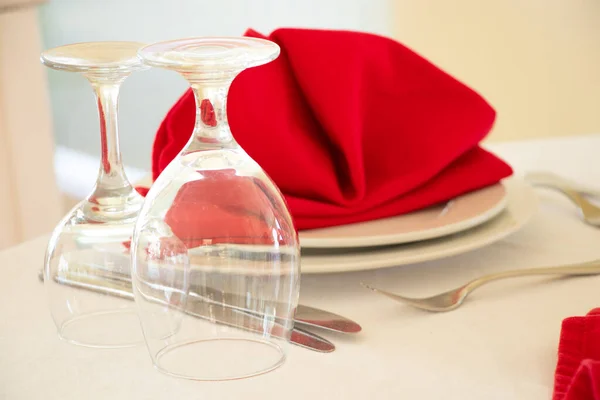 Catering services. Glasses without wine and plates with a red napkin on a white tablecloth, table for a party or wedding reception, table setting for a celebration