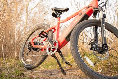 Ukrayna Dnipro 08.05 .2021 - doğadaki bir parkta duran yeni kırmızı elektrikli bisiklet, yeni teknolojiler