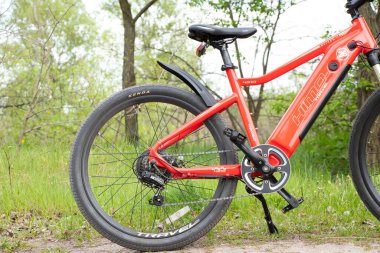 Ukrayna Dnipro 08.05 .2021 - doğadaki bir parkta duran yeni kırmızı elektrikli bisiklet, yeni teknolojiler