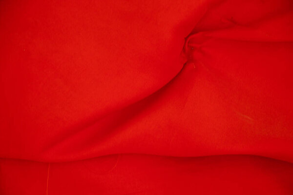 red wavy silky crumpled fabric as background close up