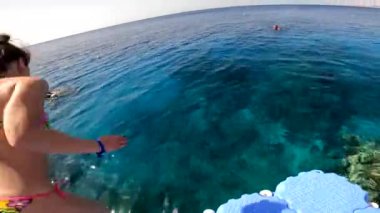 Mısır Sharm El Sheikh 04.24.2021 - bir kız iskeleden kızıl denize atlıyor, suya atlıyor