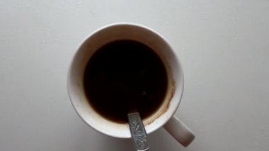 white cup with hot coffee stands on a white table in the sunlight, a cup with coffee