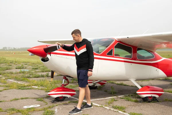 ウクライナのドニプロ市の飛行場の小さな飛行機の近くに若い男が立っています — ストック写真