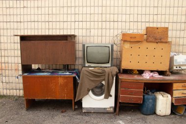 TV washing machine and writing desk are old thrown out into the street are under the wall of the house, beta equipment is on the street, rubbish