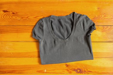 gray women's T-shirt lies on a wooden table close-up