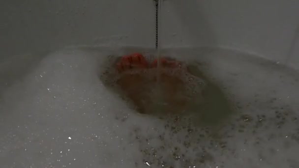 Kvinnliga fötter i ett fullt bad med tvålvatten, en flicka i badrummet tvättar sig — Stockvideo