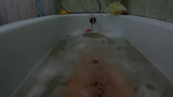 Vrouwelijke voeten in een vol bad van zeepwater, een meisje in de badkamer wast zich — Stockvideo