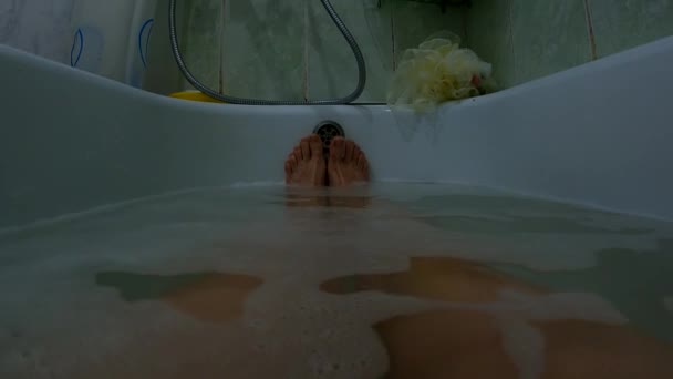 Weibliche Füße in einem Vollbad mit Seifenwasser, ein Mädchen im Badezimmer wäscht sich — Stockvideo