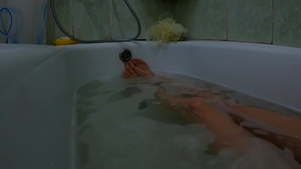 Kobiece stopy w pełnej wannie z mydlaną wodą, dziewczyna w łazience myje się — Wideo stockowe