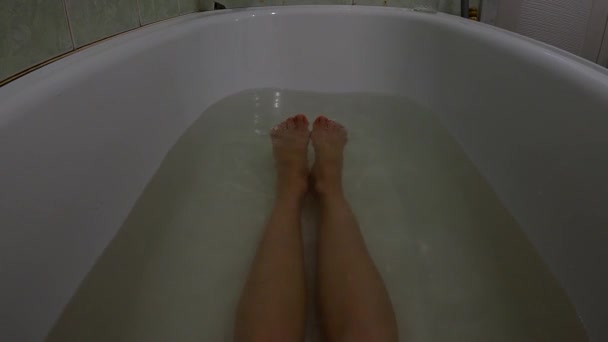 Pies femeninos en un baño completo de agua jabonosa, una chica en el baño se lava — Vídeos de Stock