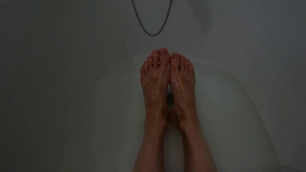 Female feet in a full bath of soapy water, a girl in the bathroom washes herself — Stock Video