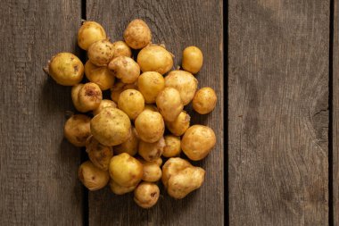 Genç kızıl saçlı, küçük soyulmuş patatesler ahşap bir masanın üzerinde uzanıyorlar.