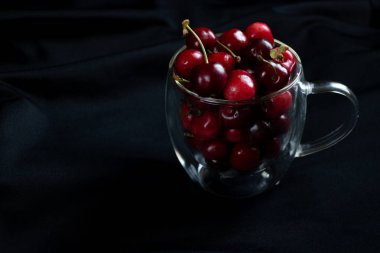 Dolu bir bardak kiraz, masada tatlı kirazlar.