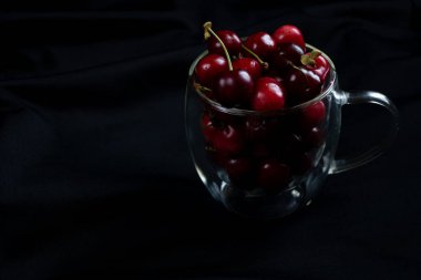Dolu bir bardak kiraz, masada tatlı kirazlar.