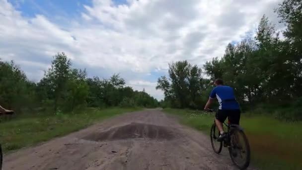 Emberek bicikliznek a parkban az út mentén az erdőben, kerékpározás, kerékpározás — Stock videók
