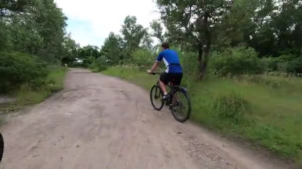 Emberek bicikliznek a parkban az út mentén az erdőben, kerékpározás, kerékpározás — Stock videók