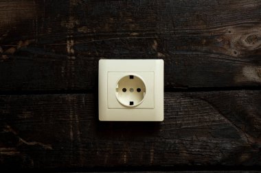 Bir evin duvarında eski yanmış bir tahta üzerinde beyaz bir soket.