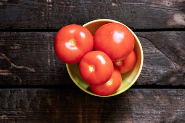 Olgun kırmızı domatesler eski ahşap bir masada yeşil bir tabakta