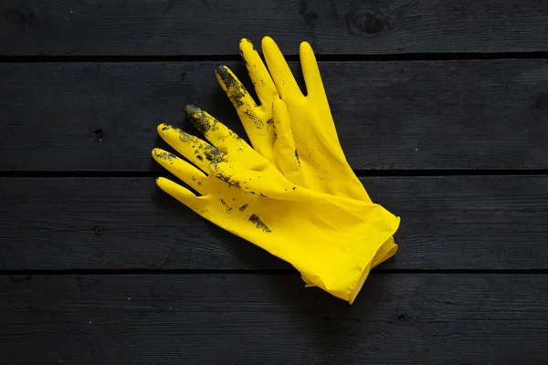 黑色漆中的黄色橡胶手套 木制地板上的黑色油漆中的黄色橡胶手套 油漆中的黄色橡胶手套 — 图库照片