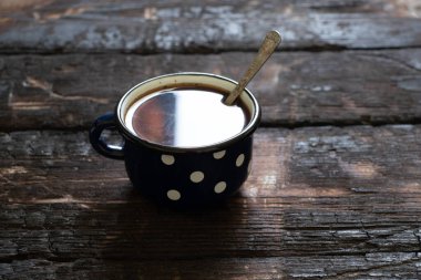 Eski ahşap bir masada beyaz bezelyeli mavi fincan, sabahları kahve.