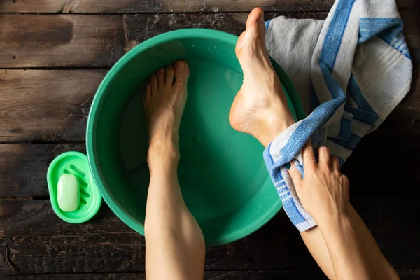 女の子は家の木製の床にある緑色のボウルに足を洗い足を洗う — ストック写真