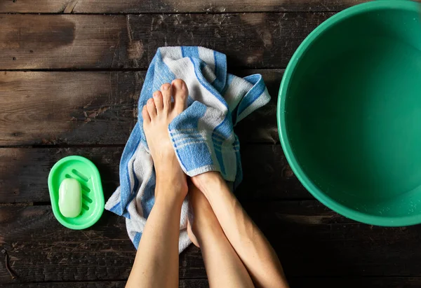 女の子は家の木製の床にある緑色のボウルに足を洗い足を洗う — ストック写真