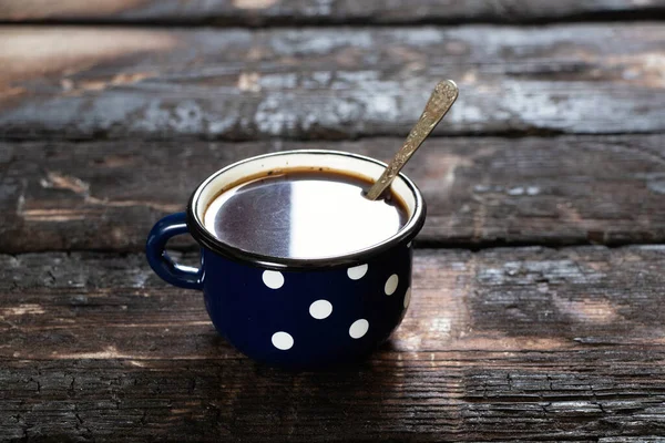 blue cup with white peas on an old wooden table, a cup with coffee in the morning