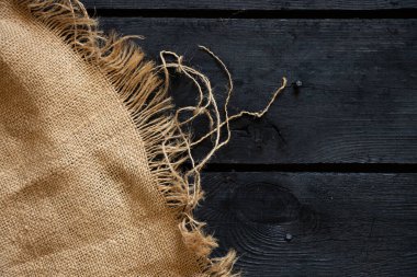 Arka plan olarak siyah tahta ve kahverengi kumaş, yerde bez, ahşap zemin