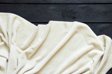 Beyaz buruşuk ekose, siyah ahşap bir zeminde arka plan olarak yatar. Tahtadaki beyaz yumuşak bez.