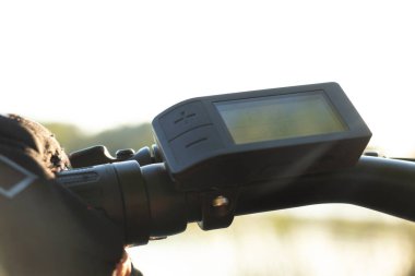 Siyah eldivenli bir kadın, parkta bir elektronik bisikletin direksiyonunu tutuyor, e-bisiklet sürüyor, bisikletin üzerinde dinleniyor.