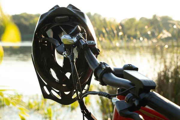 bicycle helmet on the handlebars of an e-bike at sunset in nature, cycling helmet on a bicycle