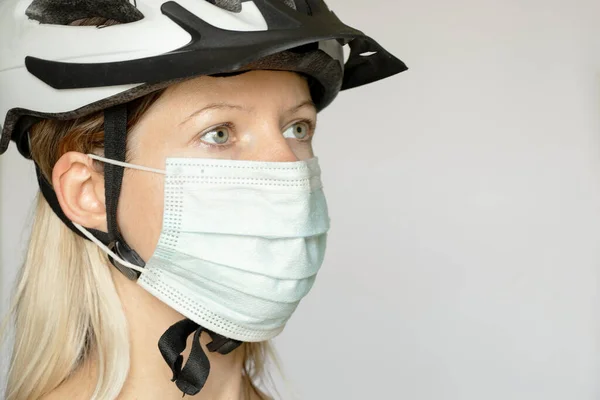 girl in a bicycle helmet and a medical mask on a white background, led with a port in a medical mask, pandemic