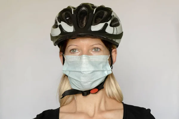 girl in a bicycle helmet and a medical mask on a white background, led with a port in a medical mask, pandemic