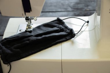 Evdeki masanın üzerindeki dikiş makinesinde tıbbi maske, tıbbi maske üretimi, dikiş.