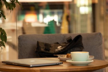 Ukrayna Dnipro 15.07.2021 - Apple MacBook dizüstü bilgisayarı ve kahve molada bir kafede masanın üzerinde bir fincan kahve, bir kafede dizüstü bilgisayar, masada dizüstü bilgisayar