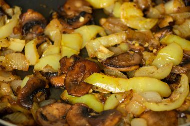 Siyah ahşap bir masada mantarlı ve soğanlı haşlanmış biber, kızartma tavasında haşlanmış sebze.