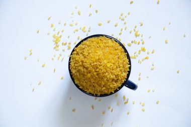 Çiğ bulgur beyaz bir tabakta bir fincanda inliyor, yulaf lapası bir fincanda.