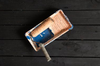Siyah ahşap zemindeki boya tepsisindeki boya silindiri, boya silindiri, tamir, boya.
