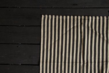 Siyah beyaz çizgili peçete, siyah tahta bir masanın üzerinde.