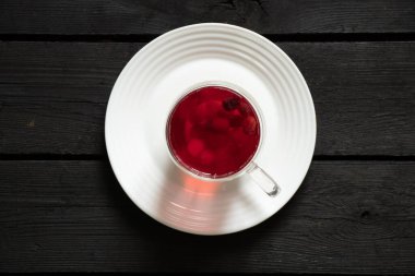 Böğürtlen kırmızısı komposto mutfaktaki siyah ahşap masada bir tabakta duruyor meyve suyu, bir fincanda komposto.