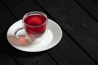 Böğürtlen kırmızısı komposto mutfaktaki siyah ahşap masada bir tabakta duruyor meyve suyu, bir fincanda komposto.